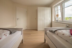 Een slaapkamer met twee bedden, een raam met uitzicht en een deur.