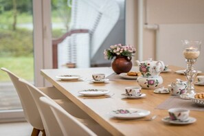 Een eettafel gedekt met bloemrijk servies, een vaas met bloemen en een kandelaar.