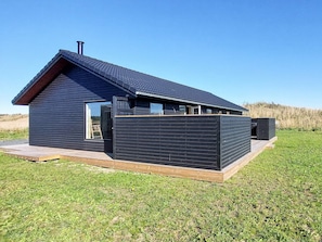 A modern house with a sloped roof, large windows, and a wooden deck. - 8 Person Holiday Home in Hirtshals (Hirtshals)