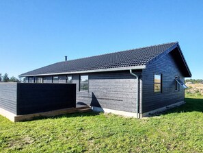 A modern single-story house with a sloped roof, a covered porch, and a fenced yard. - 8 Person Holiday Home in Hirtshals (Hirtshals)
