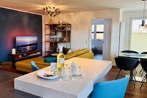 A modern living room with a sofa, a dining table, and a television. - Holiday apartment with 1 bedroom (Cuxhaven)