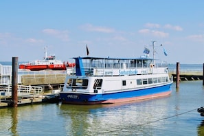 Een veerboot ligt aangemeerd aan een steiger, onder een heldere lucht.