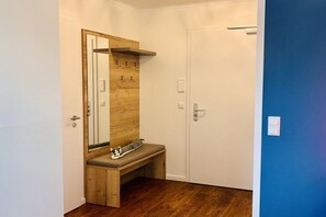 A room with a wooden bench, a mirror, a door, and a blue wall. - Holiday apartment with 1 bedroom (Cuxhaven)