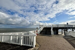 A wooden pier with a white railing, leading to a covered walkway with a staircase. - Holiday apartment with 1 bedroom (Cuxhaven)