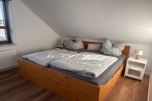 Ein Schlafzimmer mit einem hölzernen Bett, einem Nachttisch, einer Lampe und einem Fenster.