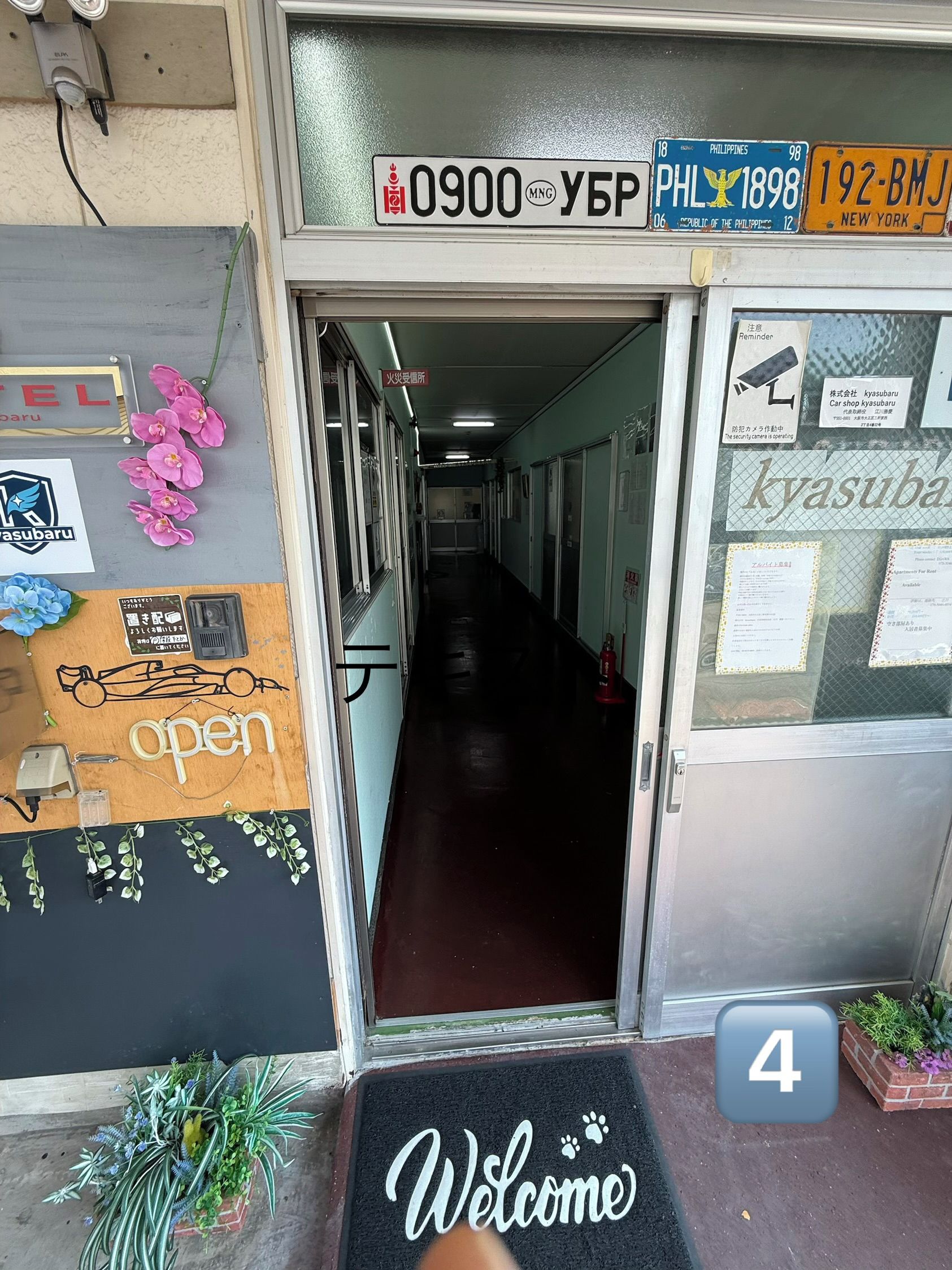 A hotel entrance with a welcome mat, a fire safety sign, and a security camera notice.