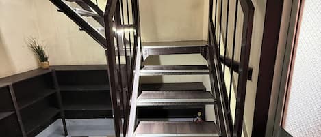 Una escalera con barandillas metálicas y peldaños de madera, que conduce a un piso superior.