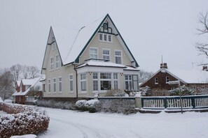 Ein großes, zweistöckiges Haus mit einem steilen Dach und einem Erkerfenster im zweiten Stock.