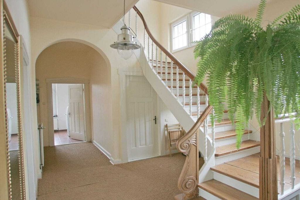A staircase with a wooden handrail and white balusters, leading to an upper floor.