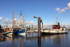 Ein Hafen mit mehreren Schiffen, darunter ein blaues Boot mit der Aufschrift 'NOR225' und ein weißes Boot mit 'Fähre'.
