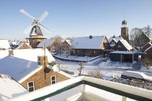 A traditional Dutch village with a windmill, brick houses, and a church tower. - Holiday home with 4 bedrooms (Jemgum-Ditzum)