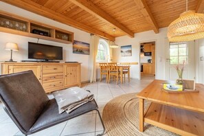 A modern living room with a television, wooden furniture, and a dining area. - Lüttje Huck/ Seeblick 2 (Aurich)