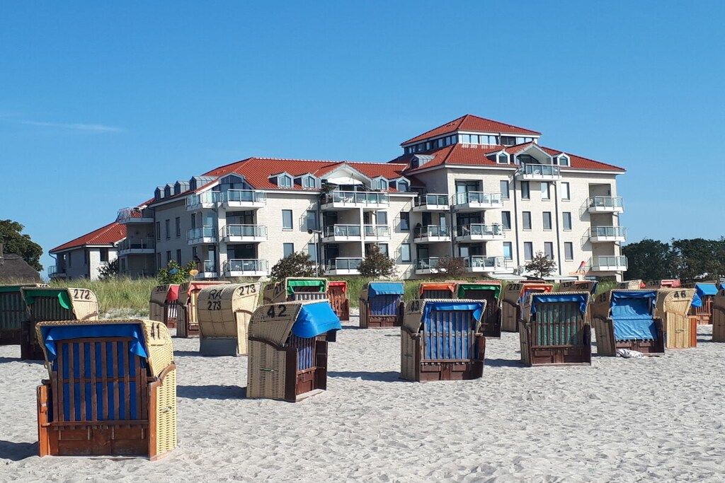Hotel na praia com várias varandas e cadeiras de praia.