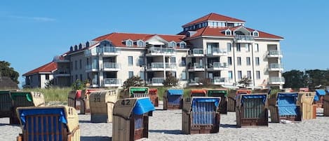 A beachfront hotel with multiple balconies and beach chairs.