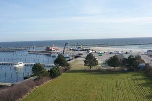 A marina with boats docked, a pier extending into the water, and a grassy area with a building in the foreground. - Holiday apartment in Damp with swimming pool (Damp)