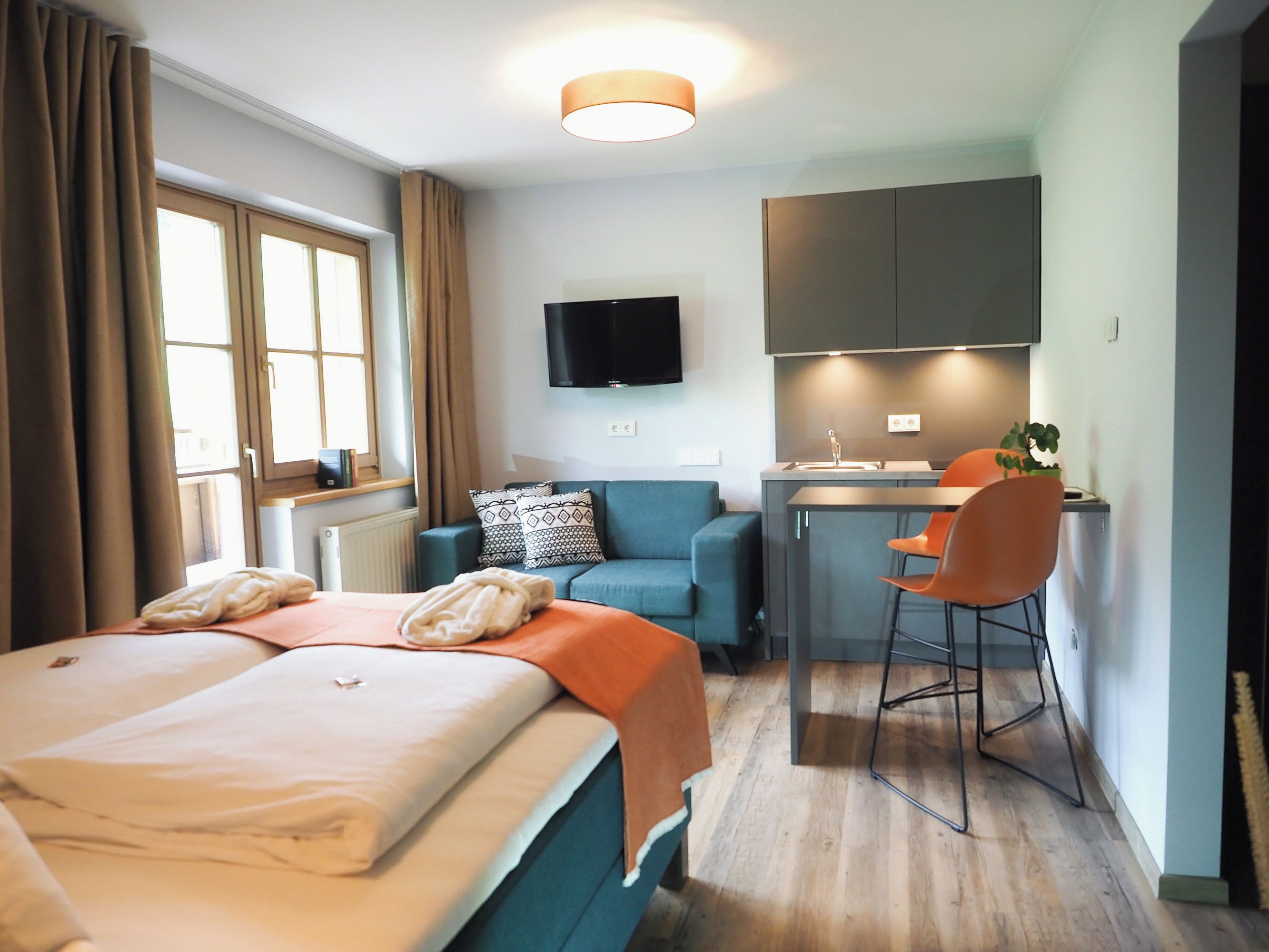 A hotel room with a bed, a desk, a chair, a television, and a window with curtains.