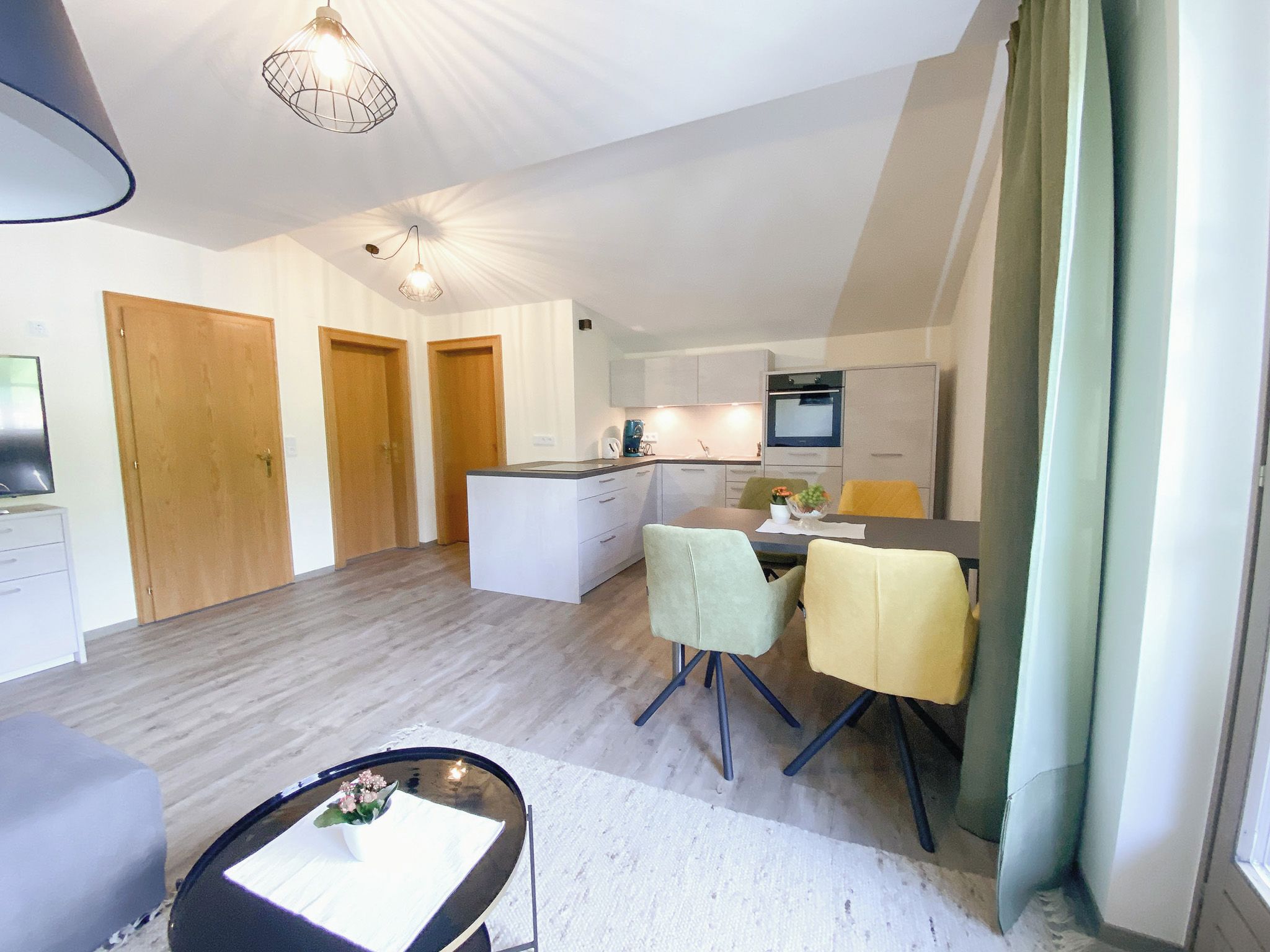 A modern apartment with a kitchen, dining area, and a living room.
