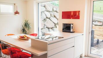 A modern kitchen with a large island, a stone wall, and a red wall decoration.