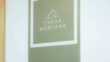 Eine Wand mit einem gerahmten Schild, auf dem 'CHESA MONTANA' steht, und einer Bergsilhouette.