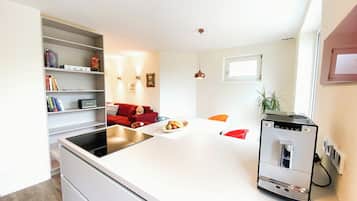 A modern kitchen with a white countertop, a red sofa, and a small dining table.