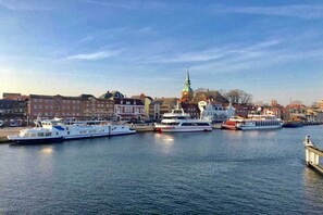 A harbor with several boats docked, a prominent church spire, and buildings along the waterfront. - Holiday apartment with 1 bedroom (Olpenitz)