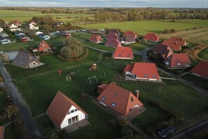 A residential area with houses, green lawns, and a playground. - Holiday home with 3 bedrooms (Dorum-Neufeld)