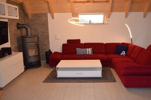 Un salon moderne avec un canapé rouge, une table basse blanche, une cheminée et une grande fenêtre.