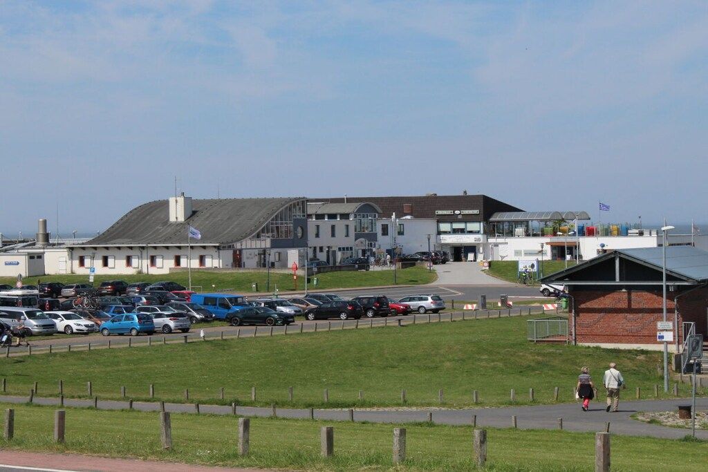 A building with a parking lot and a grassy area in front.