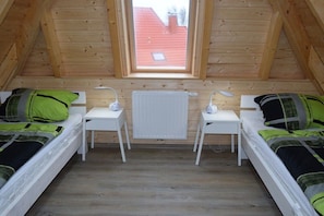 A small, cozy room with two beds, a window, and a radiator. - Holiday home with 3 bedrooms (Dorum-Neufeld)