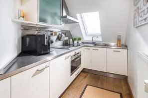 A modern kitchen with white cabinets, a stainless steel countertop, and a built-in oven. - Holiday apartment in Juist with swimming pool (Juist)
