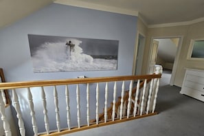 A room with a white railing, a painting of a lighthouse on the wall, and a white dresser. - Beach holiday home at Tabakshof (Sierksdorf)