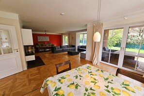 A spacious room with a large bed, a sofa, and a dining table. There is a sliding glass door leading to an outdoor area. - Beach holiday home at Tabakshof (Sierksdorf)
