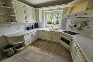 A kitchen with white cabinets, a window, and a tiled backsplash. - Beach holiday home at Tabakshof (Sierksdorf)