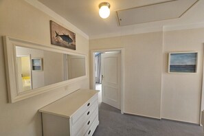 A hallway with a white dresser, a large mirror, and a painting of a fish on the wall. - Beach holiday home at Tabakshof (Sierksdorf)