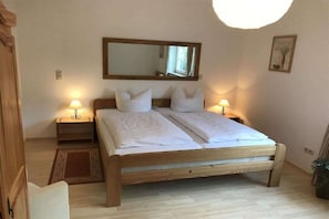 Ein Schlafzimmer mit einem hölzernen Bett, zwei Nachttischen, einem Spiegel und einem kleinen Teppich.