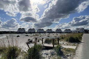 A beachside property with a wooden boardwalk leading to a row of white buildings. - Holiday apartment with 2 bedrooms (Kappeln)