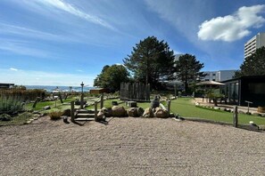 A landscaped area with a gravel path, wooden fence, and a view of the sea. - Holiday apartment with 2 bedrooms (Sierksdorf)