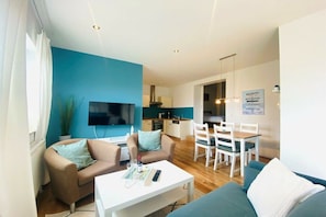 A modern living room with a flat-screen TV, sofas, a coffee table, and a dining area with chairs and a table. - Holiday apartment with 2 bedrooms (Sierksdorf)