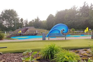 Ein Golfplatz mit einem blauen Wasserschutzgebiet, einer Brücke und einer Fahne.