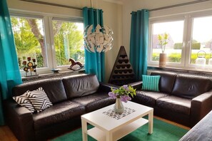 Ein Wohnzimmer mit einem braunen Ledersofa, einem weißen Couchtisch und einer dekorativen Vase mit Blumen.