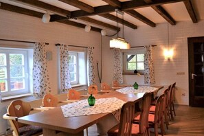 A dining area with a long table, chairs, and a hanging light fixture. - Börstel Abbey - Washhouse (Berge)