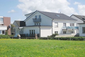 Ein zweistöckiges Wohnhaus mit Balkon, Veranda und einem gepflegten Rasen.
