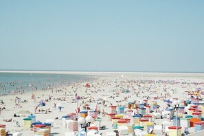 A beach with numerous colorful beach umbrellas and sun loungers. - "Beach apartment Borkum" (Borkum)