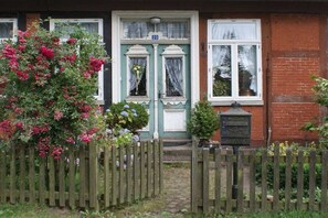 A house with a green door, a number 23, and a wooden fence. - Holiday apartment with 2 bedrooms (Neuenkirchen OT Delmsen)