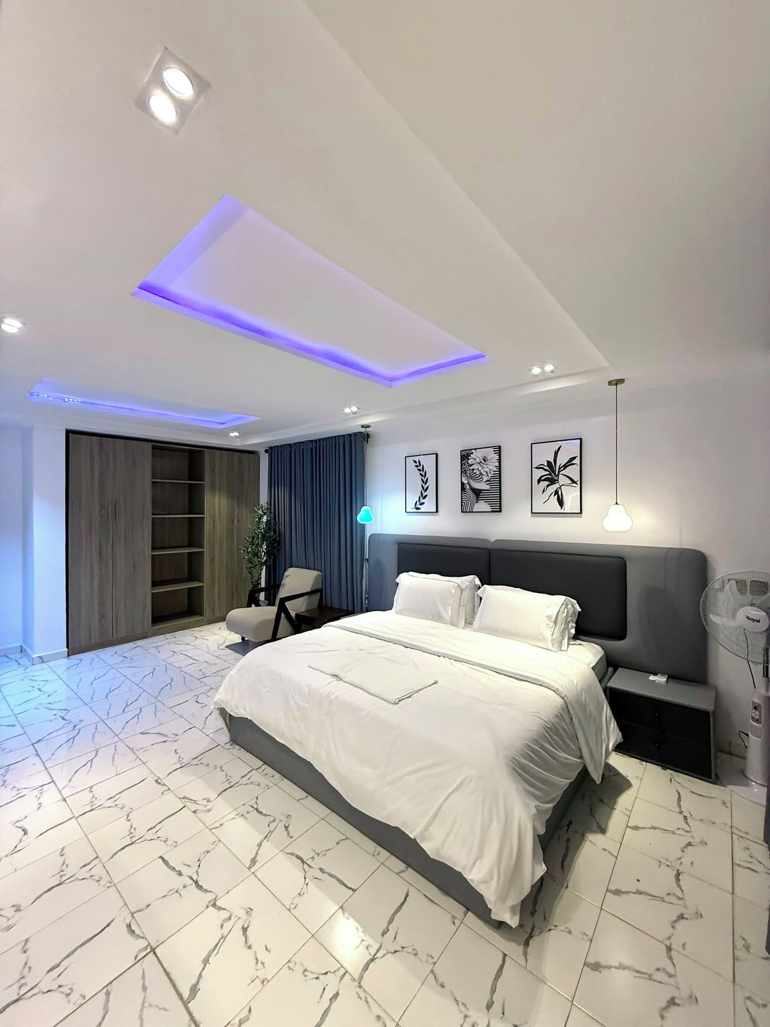 Ein modernes Schlafzimmer mit einem großen Bett, einem Kleiderschrank, einem Schreibtisch und einem Nachttisch.