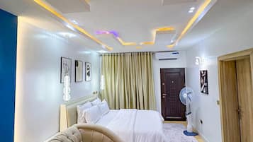 Ein modernes Schlafzimmer mit Bett, Sofa, Ventilator und einer Tür.
