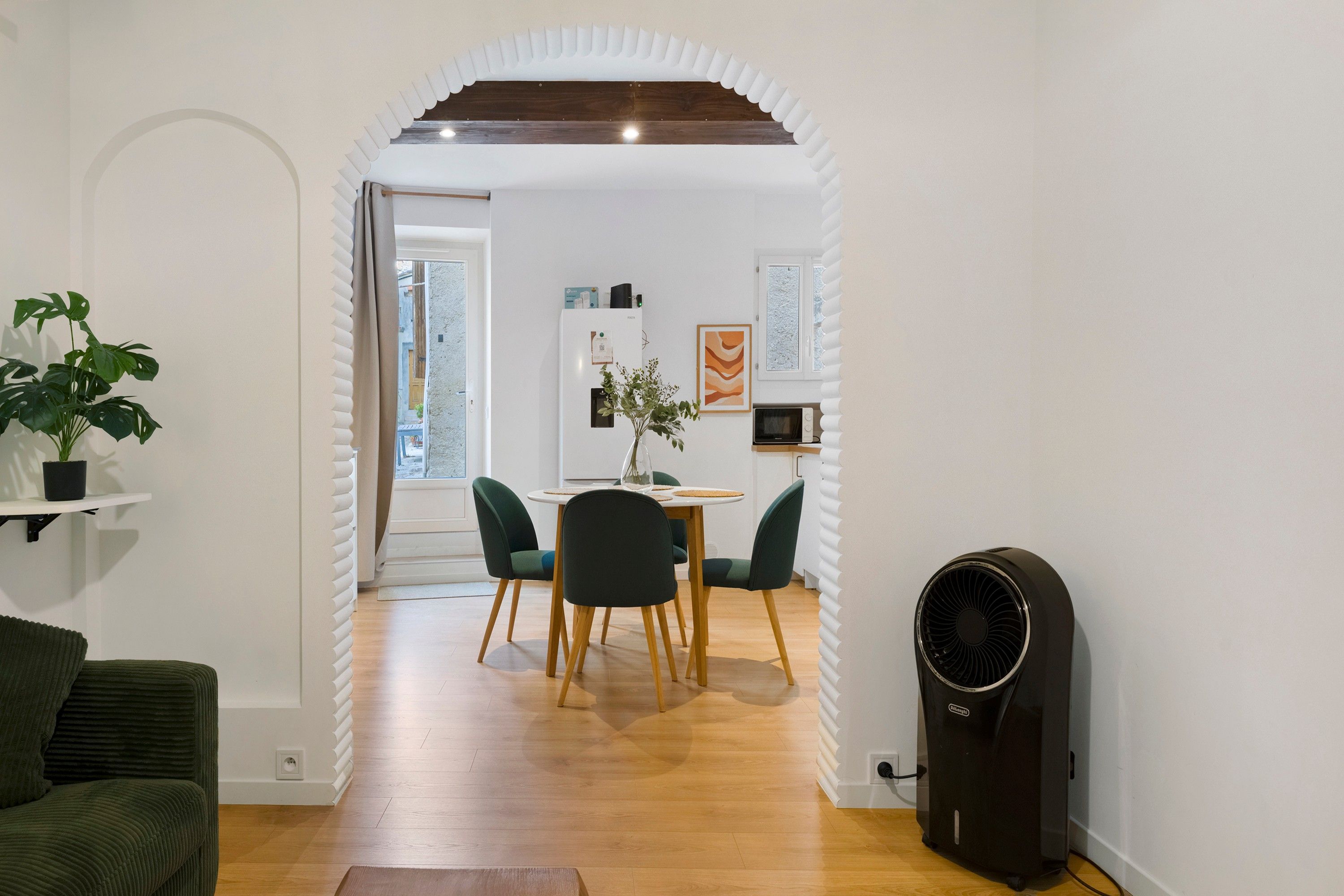 A modern interior with a dining area, a black fan, and a green plant.
