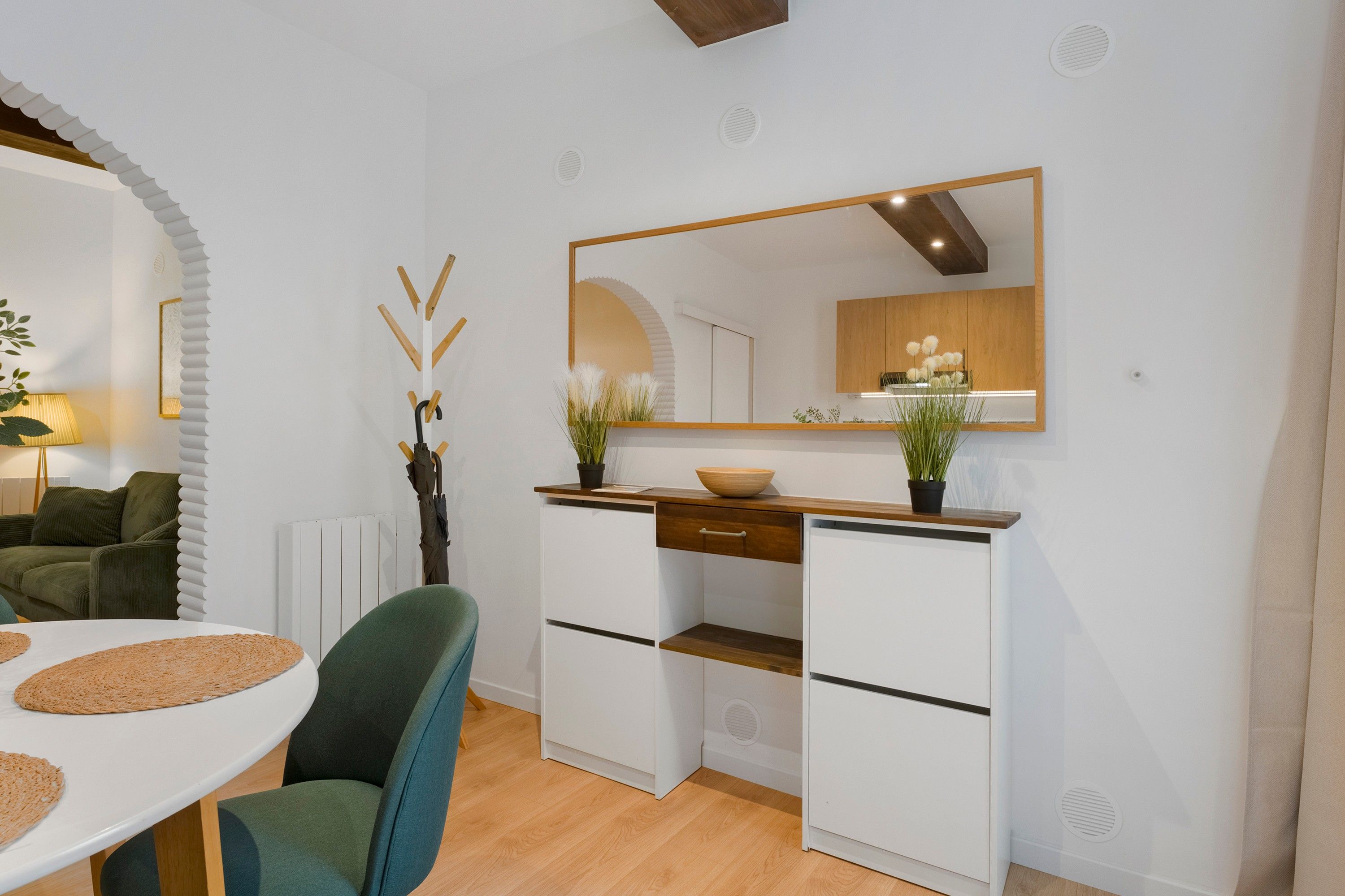 Une cuisine moderne avec des meubles blancs, un plan de travail en bois et un grand miroir au-dessus de l’évier.