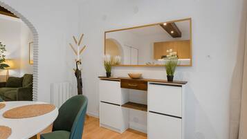 Une cuisine moderne avec des meubles blancs, un plan de travail en bois et un grand miroir au-dessus de l’évier.