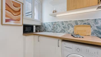 A compact kitchen with a washing machine, a microwave, and a sink.
